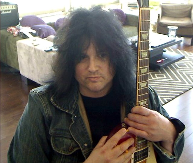 Benny Doro holding a guitar at home